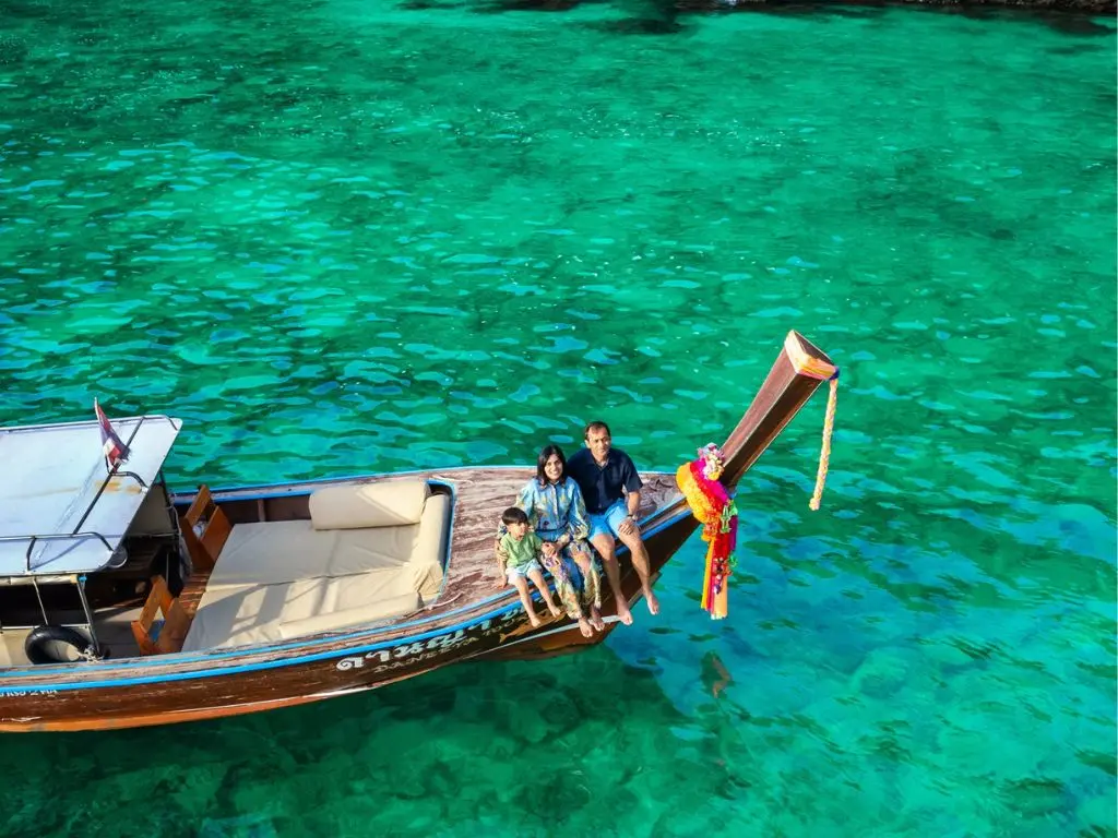 Casal relaxando em barco long tail sobre águas turquesa em Nuy Bay. O que fazer em Phi Phi. Passeios em Phi Phi.