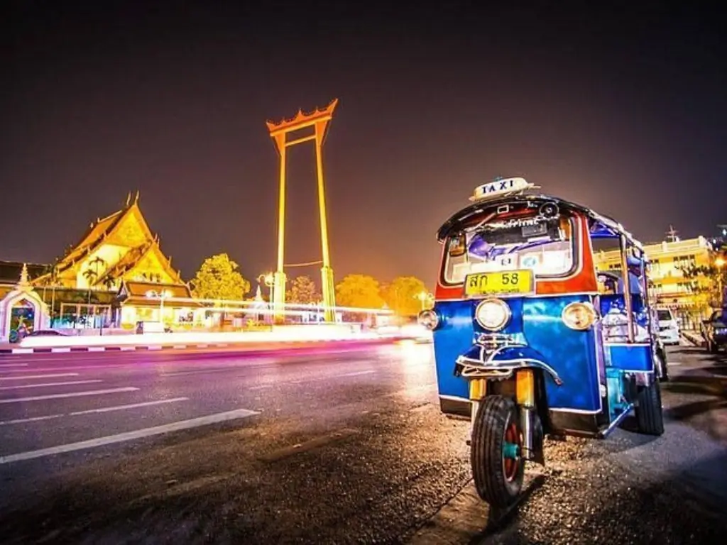 Passeio noturno de tuk tuk pelas ruas iluminadas de Bangkok, com templos e monumentos ao fundo